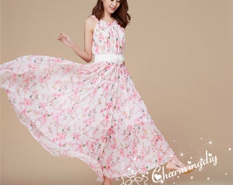 May include: A white maxi dress with a pink floral print and a white belt. The dress has a halter neckline and a flowy skirt.