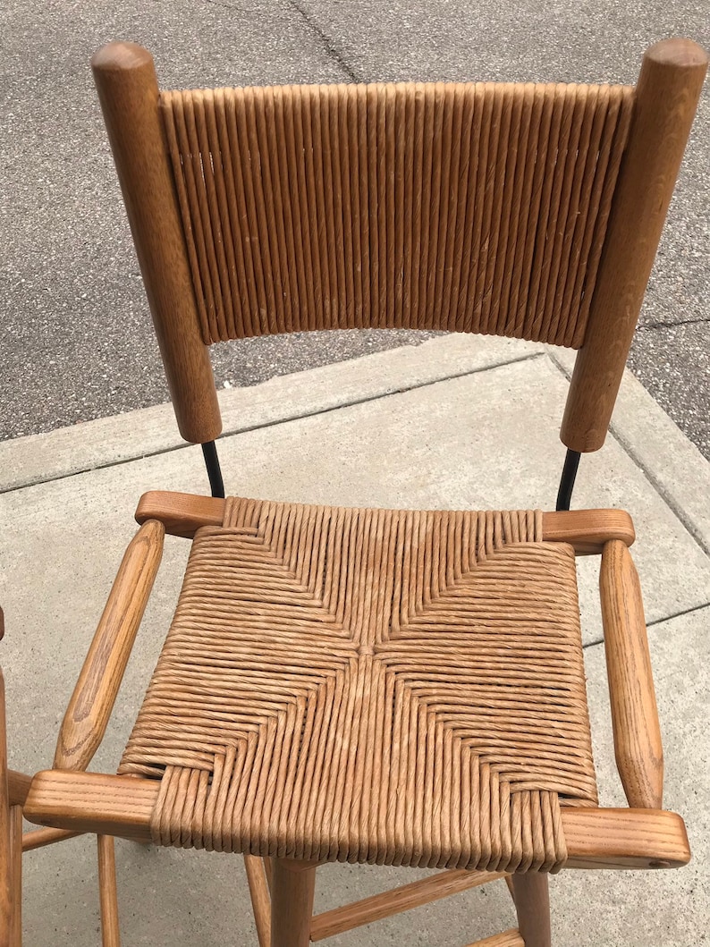 May include: A wooden bar stool with a woven cane seat and back. The stool has a dark brown finish and a black metal frame.