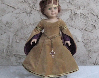 May include: A doll wearing a gold velvet dress with purple sleeves and a gold crown. The dress has a gold chain belt with a cross pendant.