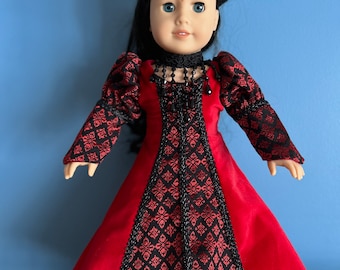 May include: A doll wearing a red and black dress with a black lace trim. The dress has a fitted bodice and a full skirt. The doll has black hair and blue eyes.