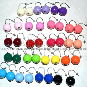 May include: A selection of colourful round earrings in shades like cream, purple, pink, red, green, yellow, orange, blue, and black. Each earring features a silver-tone hook. The image includes the Etsy shop URL.