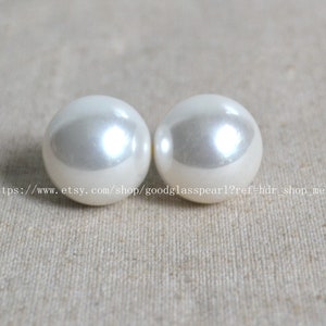 Puede incluir: Dos grandes pendientes redondos de color blanco perla.