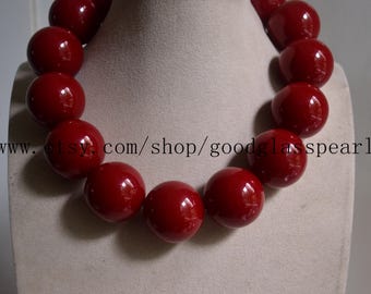 Può includere: Una collana audace con grandi perline rotonde e lucide di colore rosso. Le perline sono infilate insieme per creare un accessorio grosso e accattivante. La collana è esposta su un busto dai toni neutri.