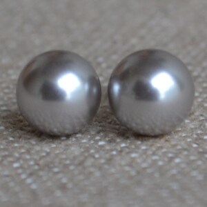 Op de afbeelding: Een paar zilveren parel oorbel studs. De parels zijn rond en hebben een gladde, glanzende afwerking.