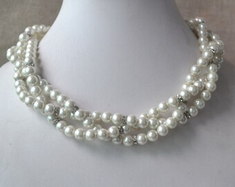 May include: A triple strand faux pearl necklace with small clear rhinestone accents.