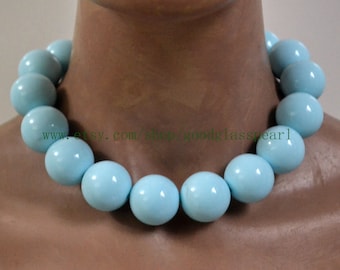 May include: A light blue glass bead necklace with large, round beads. The necklace is on a mannequin's neck.