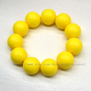 May include: A yellow beaded bracelet with 10 round beads. The bracelet is made of glass beads.