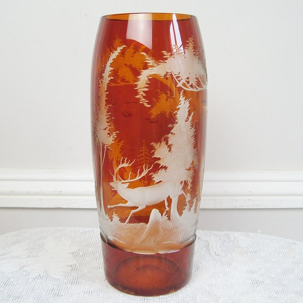 Beau vase en verre orangé avec motif de cerf dans un paysage de forêt