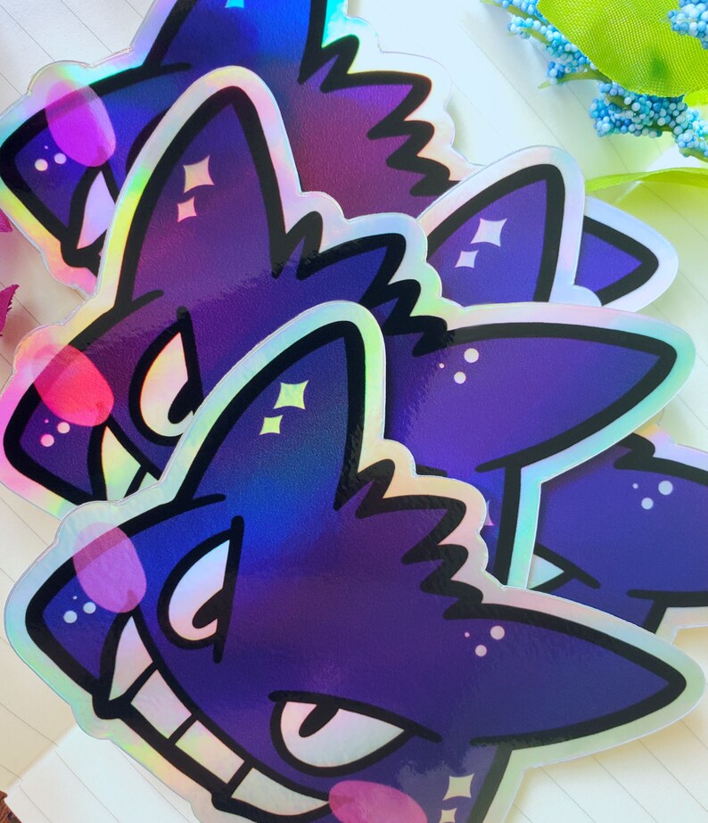 May include: Three iridescent purple and black stickers of a cartoon wolf with a toothy grin and sparkling eyes.