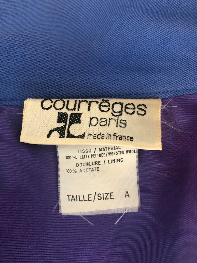 May include: A white tag with black text that reads "courr&egrave;ges paris made in france" and details the fabric composition: "TISSU / MATERIAL 100% LAINE PEIGNEE/WORSTED WOOL DOUBLURE / LINING 100% ACETATE TAILLE/SIZE A".