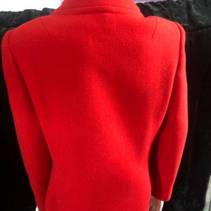 K&ouml;nnte beinhalten: Ein rotes Wollkost&uuml;m aus Jacke und Rock. Die Jacke hat einen Kragen und lange &Auml;rmel. Der Rock ist knielang.
