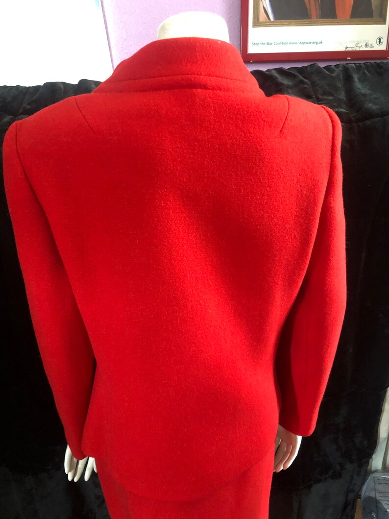 K&ouml;nnte beinhalten: Ein rotes Wollkost&uuml;m aus Jacke und Rock. Die Jacke hat einen Kragen und lange &Auml;rmel. Der Rock ist knielang.