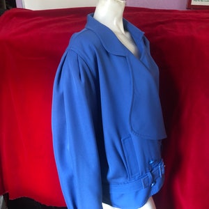 May include: A blue blazer with a long sleeve, a collar, and a belt with a buckle. The blazer is on a white mannequin.