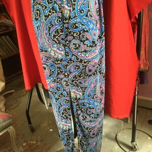 May include: A long black skirt with a paisley pattern in shades of blue, pink, and white. The skirt has a center slit and is made of a soft, flowing fabric.