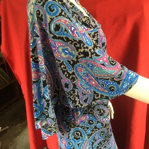 May include: A black, blue, and pink paisley print dress with a ruffled neckline and 3/4 sleeves.