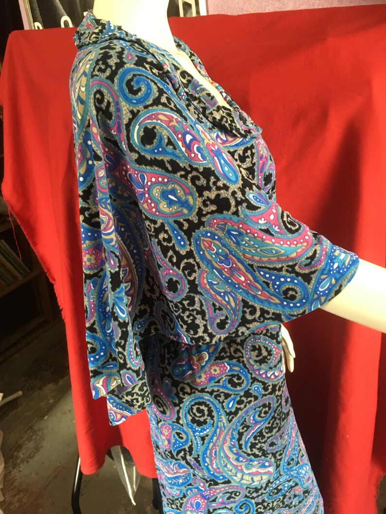 May include: A black, blue, and pink paisley print dress with a ruffled neckline and 3/4 sleeves.
