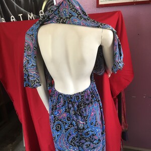 May include: A black and blue paisley print maxi dress with a halter neckline and a low back. The dress is on a mannequin.