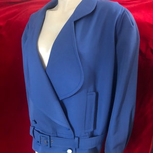 May include: A blue blazer with a long, pointed collar and a belt. The blazer has a single button closure and two pockets.