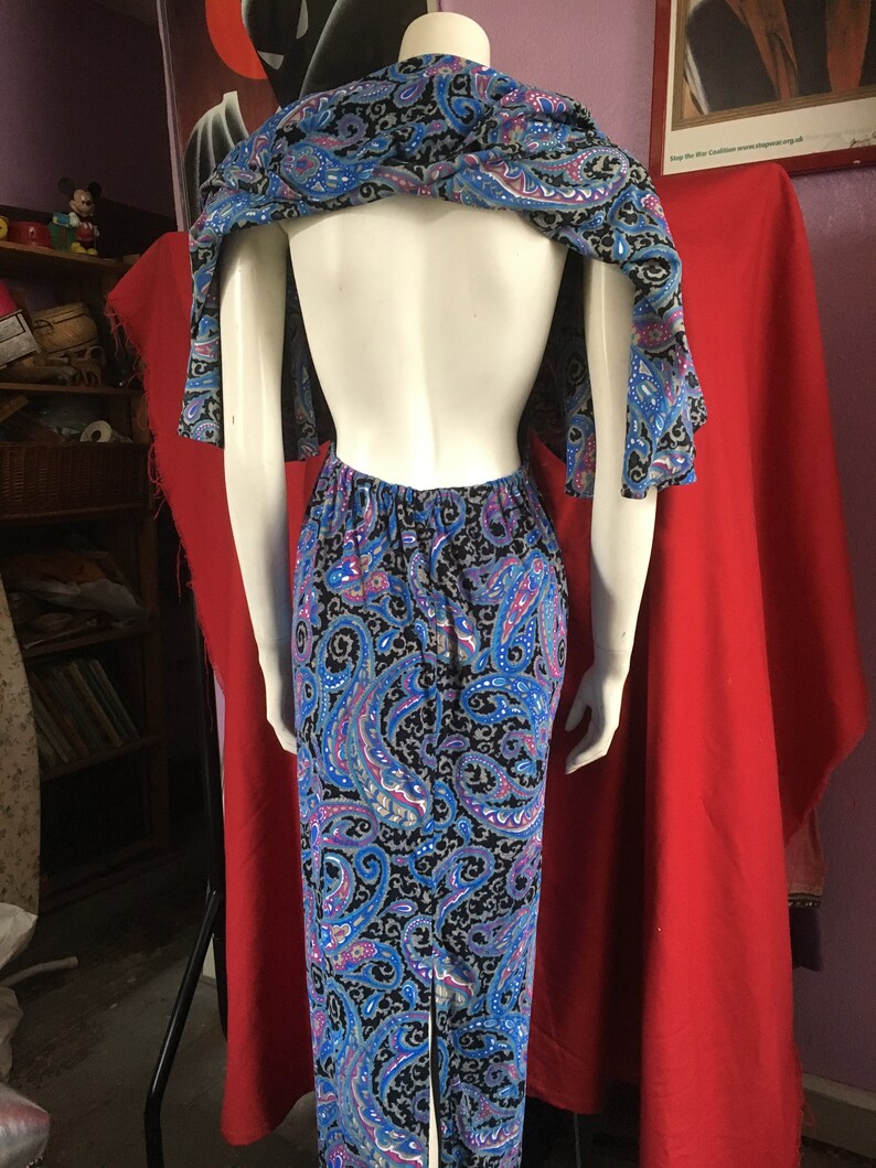 May include: A blue and black paisley print maxi dress with a low back and a matching shawl. The dress has a fitted bodice and a flowing skirt.