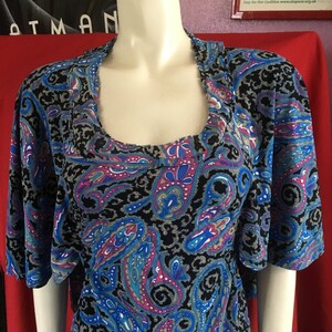 May include: A blue, black, pink, and white paisley print top with short sleeves and a scoop neck.