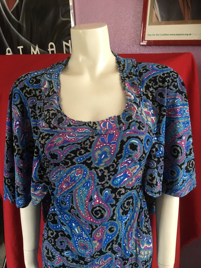 May include: A blue, black, pink, and white paisley print top with short sleeves and a scoop neck.