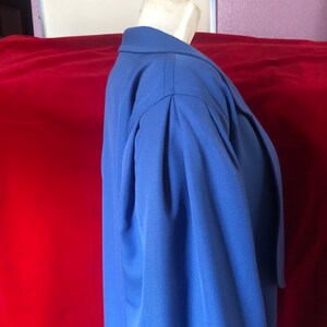 May include: A blue blazer with long sleeves and a collar. The blazer has a single button closure and a belt at the waist.