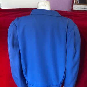 May include: A blue blazer with a belt. The blazer has long sleeves and a collar.