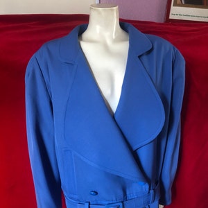 May include: A blue blazer with a large collar, a double-breasted closure, and a matching belt with a gold buckle.