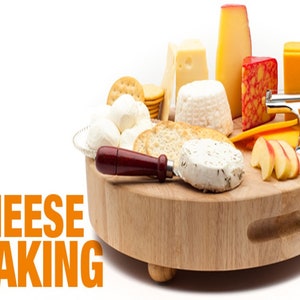 Op de afbeelding: Een houten kaasplank met een assortiment kazen, crackers en appels. De plank heeft een handvat en vier poten. De tekst "CHEESE MAKING" is zichtbaar in de linkerbenedenhoek van de afbeelding.