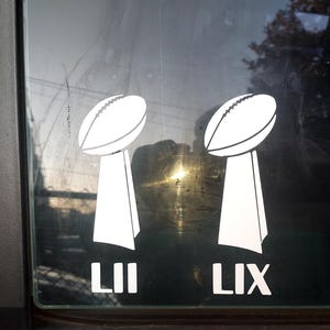 May include: Two white vinyl decals of the Super Bowl trophy, one with the Roman numeral LII and the other with the Roman numeral LIX.