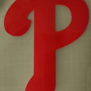 May include: A bright red letter "P" logo, with a distinctive curved top and a flowing lower portion. The design is a solid color and appears to be a sticker or decal, likely for sports or fan merchandise.