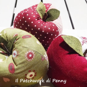 May include: Three handmade fabric apples in red, green, and white with a patchwork design. The apples have a stem and leaf made of felt.