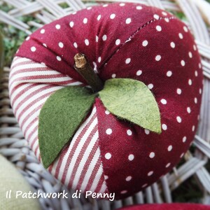 May include: A red and white polka dot fabric apple with green felt leaves. The apple is sewn with a white and red striped fabric.