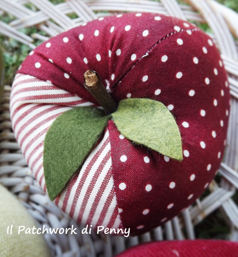 May include: A red and white polka dot fabric apple with green felt leaves. The apple is sewn with a white and red striped fabric.