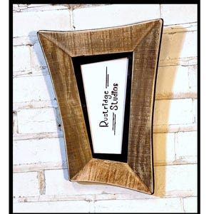 May include: A rustic wooden picture frame with a unique, asymmetrical shape. The frame has a distressed, weathered appearance with visible wood grain. The interior features a black border surrounding a white space with the text "Dustridge Studios".