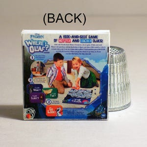 May include: A Frozen Where's Olaf game box with a blue and white background. The box features a picture of two children playing the game, with the text "A Kids-And-Seek Game of Hotter and Colder Clues!" on the front.