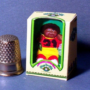 May include: A Cabbage Patch Kid doll in a yellow and red jersey with the number 31 on it. The doll is in a cardboard box with the Cabbage Patch Kids logo.