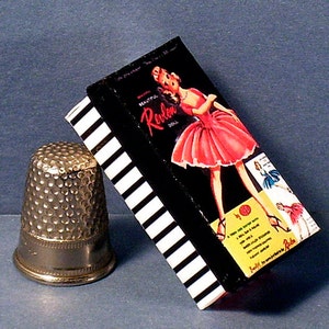 May include: A vintage box of Revlon hosiery with a black and white striped design. The box features a woman in a pink dress and the text "Beautiful Revlon Hosiery".