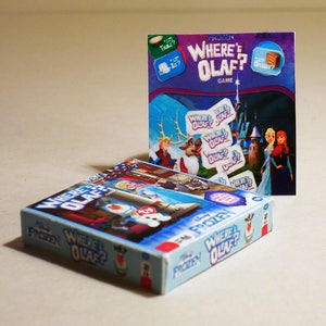 May include: A blue and white board game box with the title "Frozen Where's Olaf?"  The box features Olaf, Elsa, and Anna from the Disney movie Frozen. The game is a matching game where players try to find the matching Olaf cards.