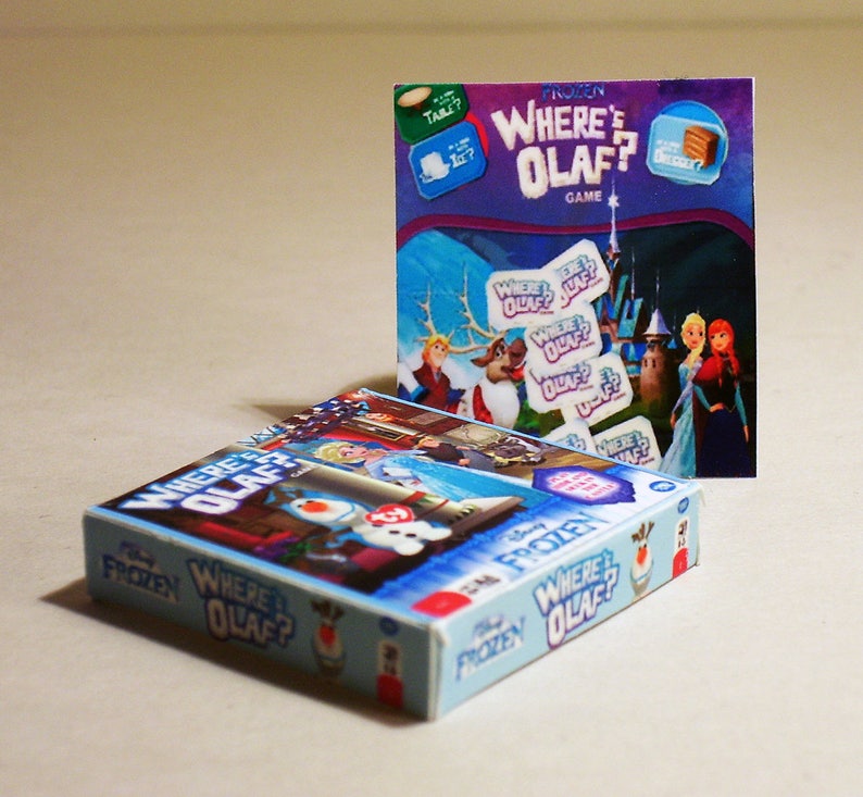 May include: A blue and white board game box with the title "Frozen Where's Olaf?"  The box features Olaf, Elsa, and Anna from the Disney movie Frozen. The game is a matching game where players try to find the matching Olaf cards.