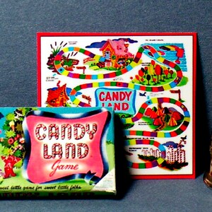 Pu&ograve; includere: Gioco da tavolo vintage Candy Land con un tabellone di gioco colorato e una scatola con una casa rosa e blu con un design a bastoncino di zucchero. La scatola riporta la scritta "Candy Land Game" e "A sweet little game for sweet little folks".