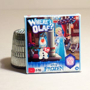 May include: A blue and white game box featuring Olaf from Disney's Frozen. The box has the words "Where's Olaf?" and "Disney Frozen" on it. The game is for ages 4 and up.