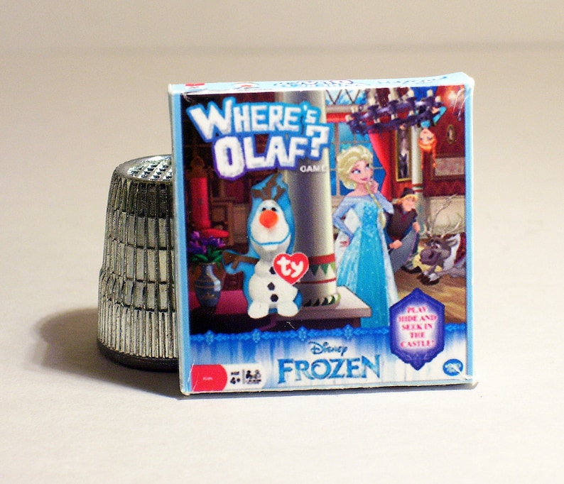 May include: A blue and white game box featuring Olaf from Disney's Frozen. The box has the words "Where's Olaf?" and "Disney Frozen" on it. The game is for ages 4 and up.