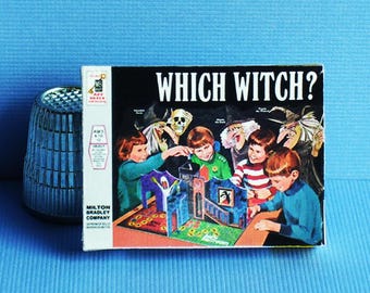May include: A miniature Which Witch? board game box featuring a colorful illustration of children playing with a 3D game board, positioned next to a metallic silver thimble. The box displays the Milton Bradley Company logo and text.