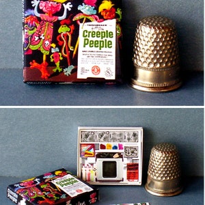 K&ouml;nnte beinhalten: Ein Vintage-Spielzeugset von Creepe Peeple mit einer Schachtel, einem Projektor und einem Bogen Aufkleber. Die Schachtel zeigt eine farbenfrohe Illustration der Creepe Peeple-Charaktere. Der Projektor ist wei&szlig; mit einem durchsichtigen Plastikbildschirm und einem roten Creepe Peeple-Logo. Die Aufkleber sind bunt und zeigen verschiedene Creepe Peeple-Charaktere.
