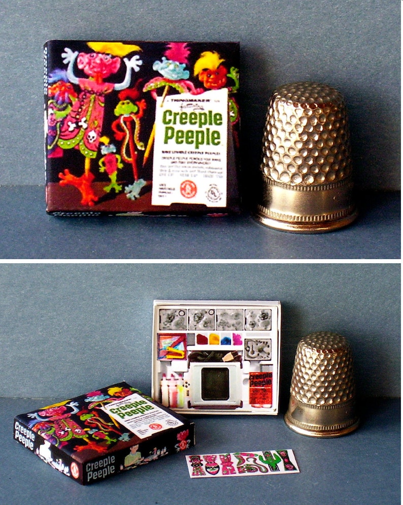 K&ouml;nnte beinhalten: Ein Vintage-Spielzeugset von Creepe Peeple mit einer Schachtel, einem Projektor und einem Bogen Aufkleber. Die Schachtel zeigt eine farbenfrohe Illustration der Creepe Peeple-Charaktere. Der Projektor ist wei&szlig; mit einem durchsichtigen Plastikbildschirm und einem roten Creepe Peeple-Logo. Die Aufkleber sind bunt und zeigen verschiedene Creepe Peeple-Charaktere.