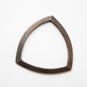 May include: A triangular metal ring with a textured surface. The ring is a light bronze color.