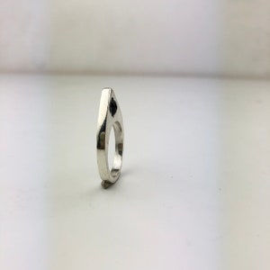 May include: A silver ring with a black stone set in the center of the top. The ring is shaped like a teardrop.