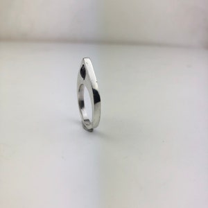 May include: A silver ring with a black stone set in the center. The ring is shaped like a teardrop and has a smooth, polished finish.