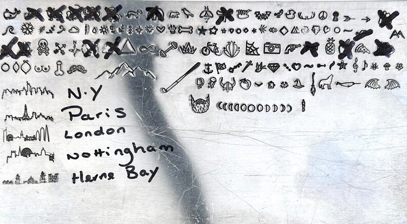 May include: A metal plate with a variety of hand-drawn symbols and city names including New York, Paris, London, Nottingham, and Herne Bay.